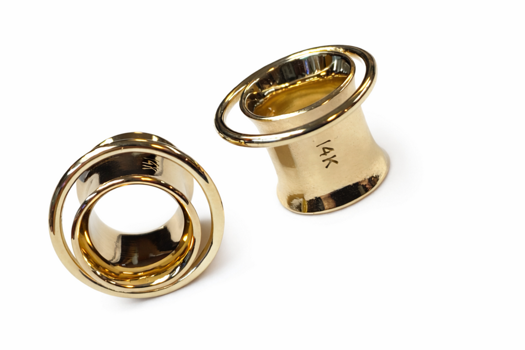 Two gold ear gauges on a white background